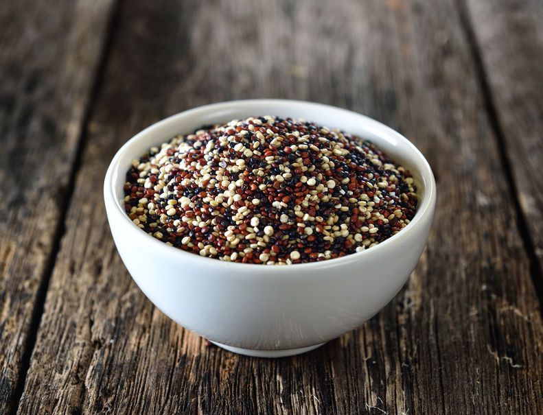 Quinoa seeds in bowl on wood