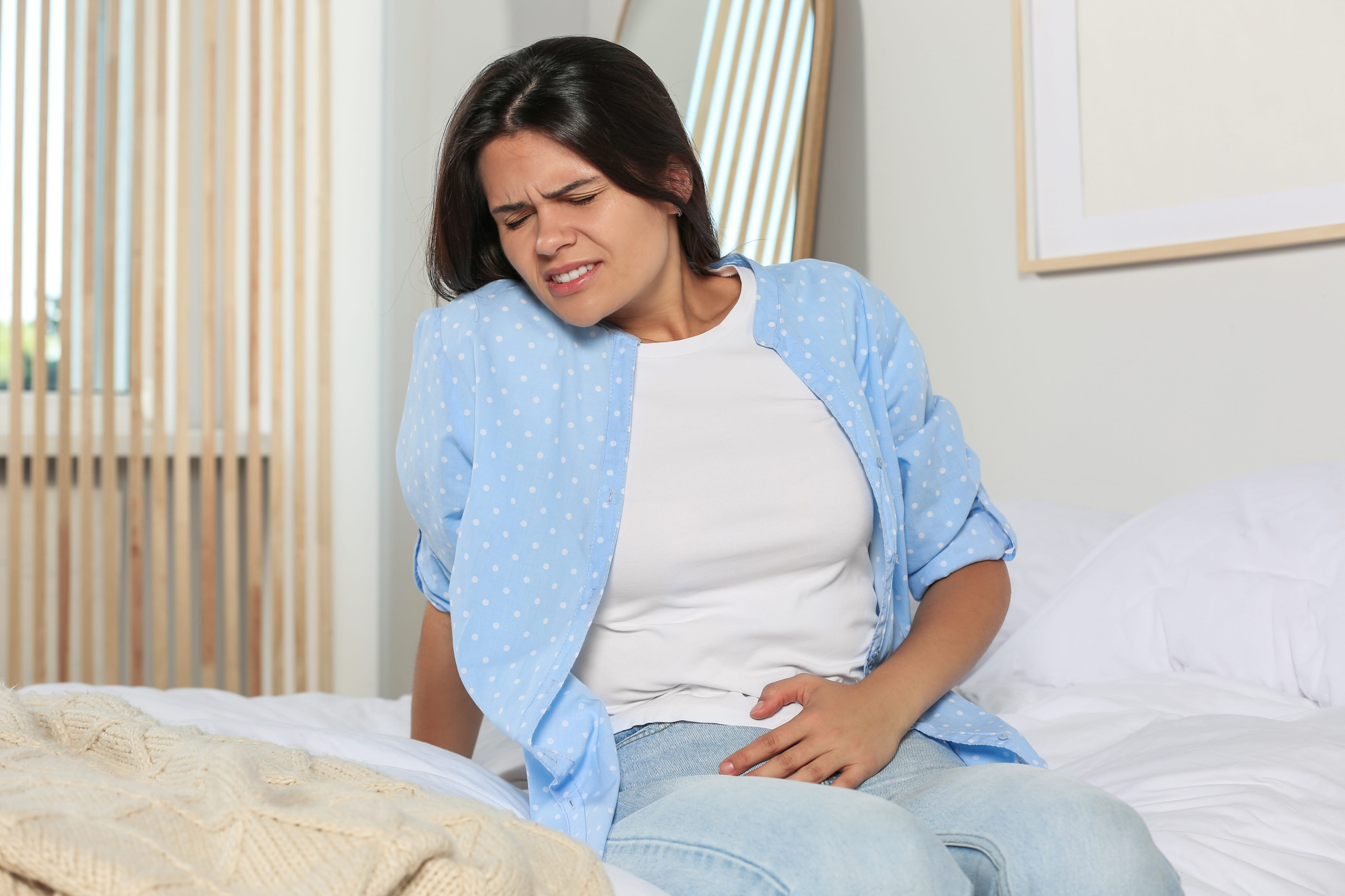 infecciones urinarias Young woman suffering from cystitis on bed at home