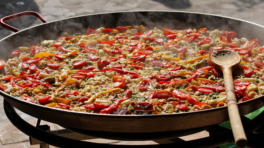 cooking Spanish paella with wooden spoon