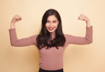 Usos de la creatina més enllà de l’esport Beautiful young Asian woman flex bicep on beige background