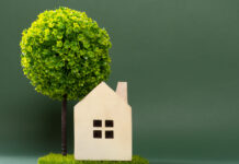 Cómo ahorrar energía mediante un consumo eficiente a house model on green grass with a tree on back