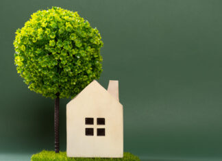 Cómo ahorrar energía mediante un consumo eficiente a house model on green grass with a tree on back