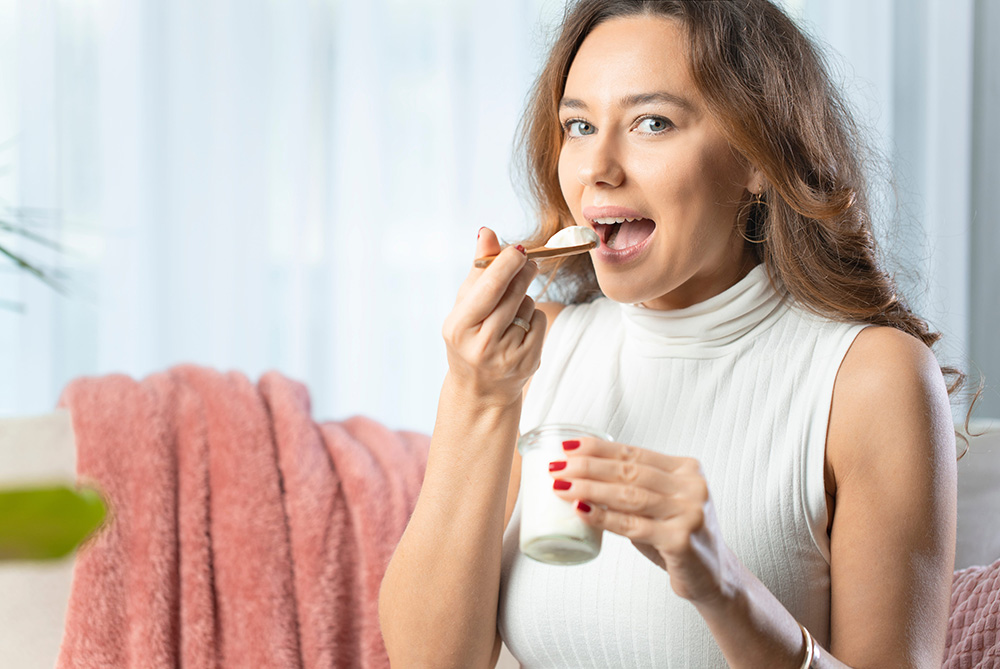 Healthy lifestyle. Portrait of beautiful smiling woman tasting fresh yogurt.
