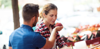 Frutas de hueso ecológicas, el mejor sabor del verano Shot of beautiful young customer smelling nectarina in health grocery shop.