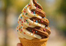 Tentempiés saludables en verano: cómo alimentar e hidratar a los más pequeños Ice cream cone in female hand with colorful sprinkles on it.