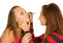 Qué es la cosmeticorexia y cómo afecta a los más jóvenes Two teenage girls dye their eyelashes isolated on white