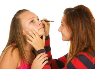 Qué es la cosmeticorexia y cómo afecta a los más jóvenes Two teenage girls dye their eyelashes isolated on white