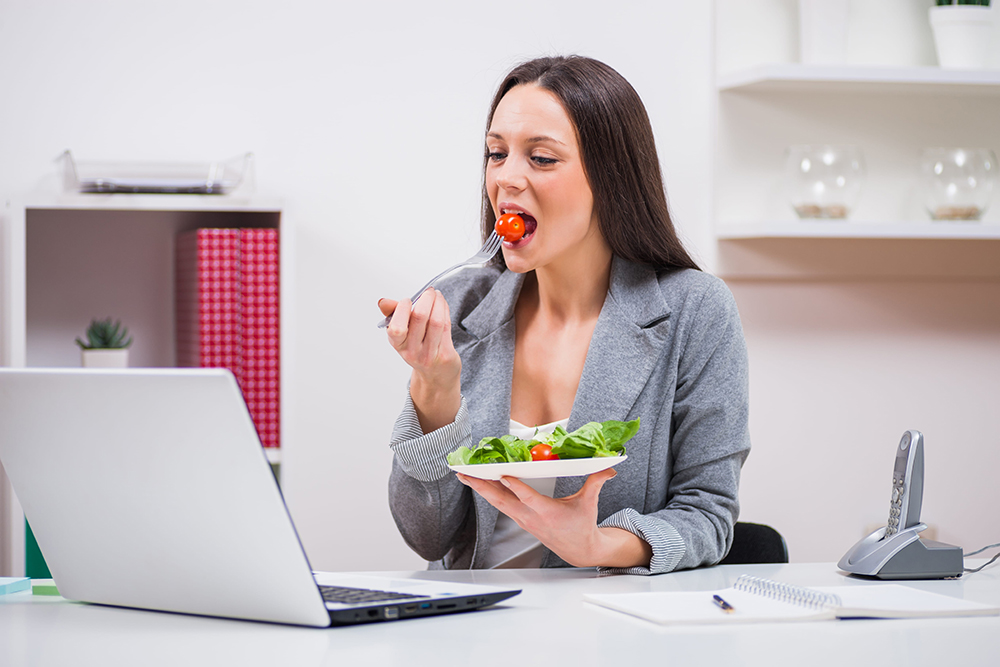 Mujer comiendo una ensalada como parte de una alimentación saludable para la piel