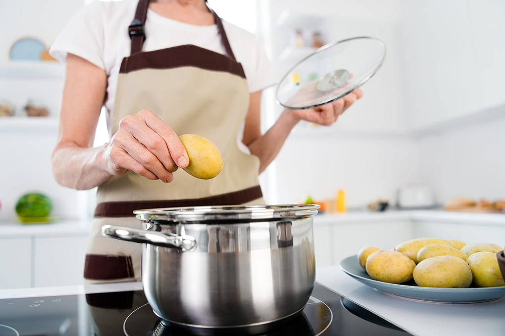 Cropped photo of lady cook potatoes wear apron white t-shirt at kitchen alone